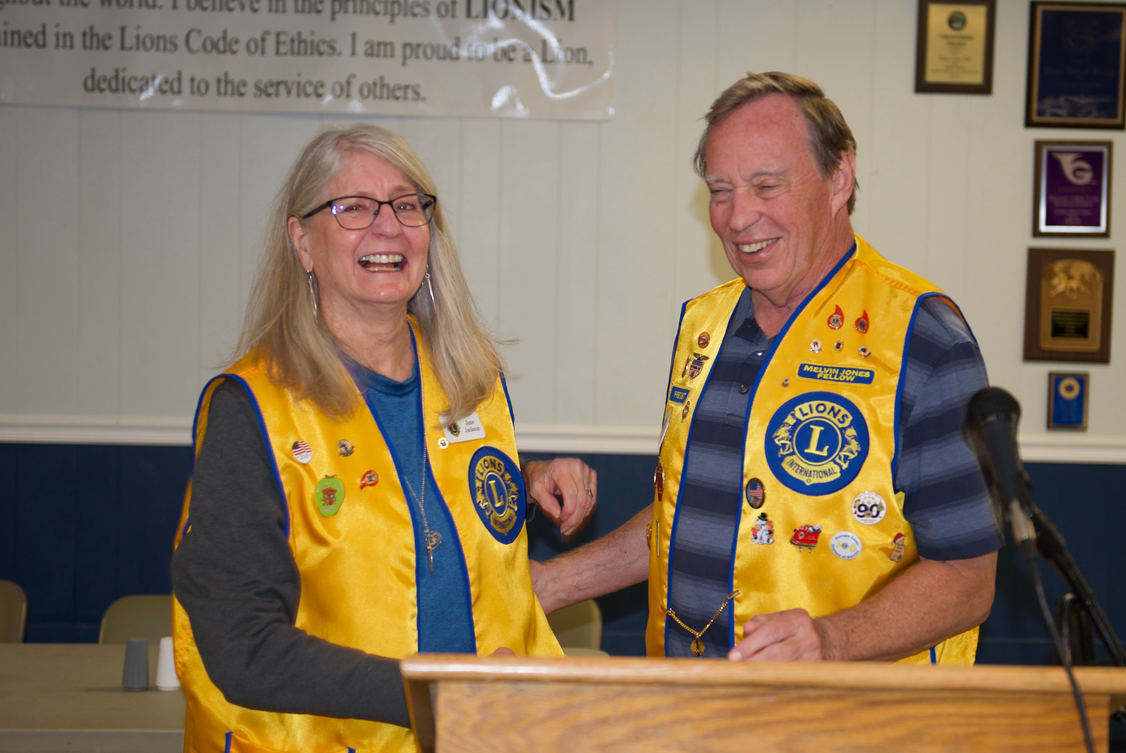 Two Lions Club members laughing together indoors at the ceremony