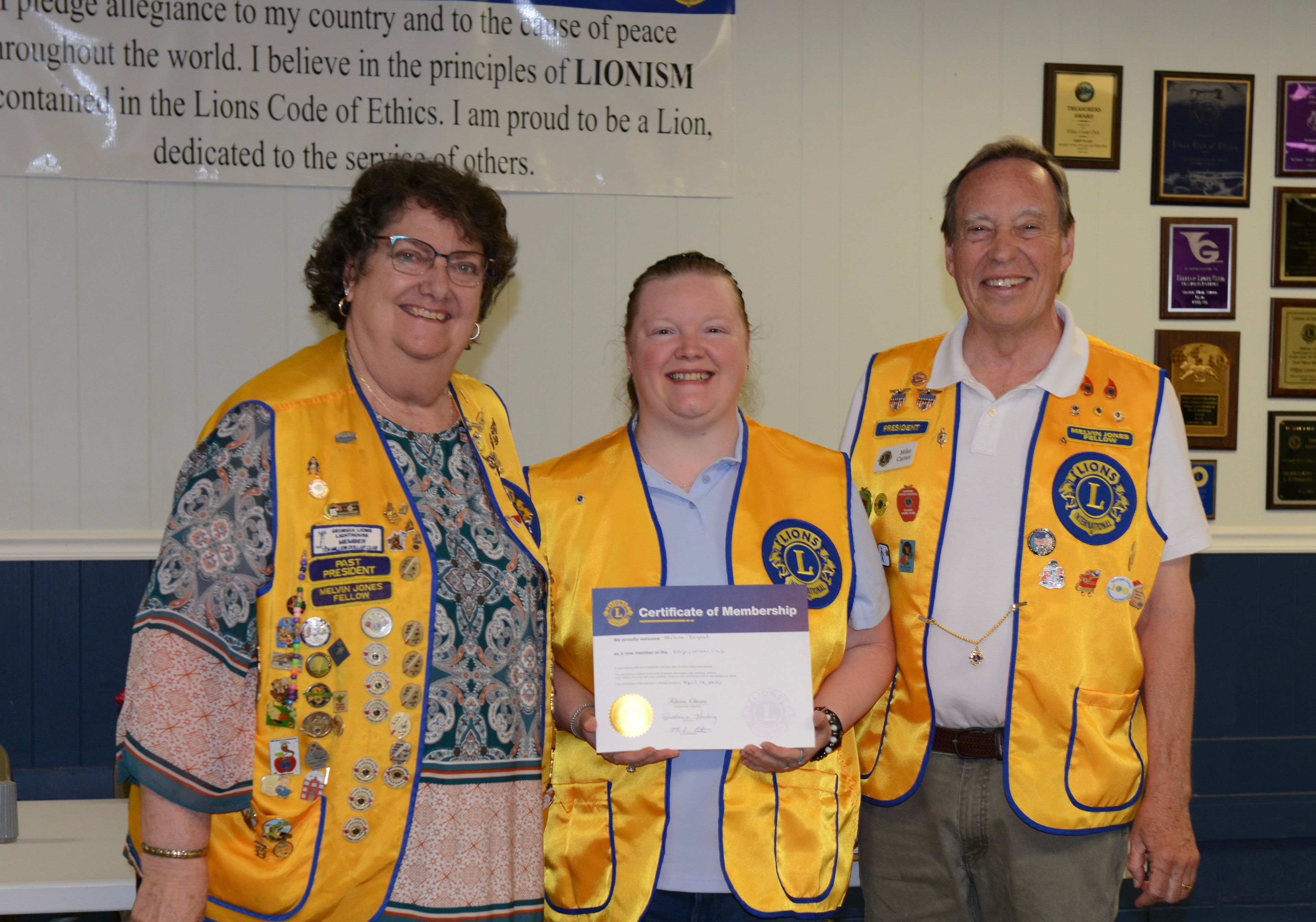 Lions Club members holding a membership certificate at the ceremony
