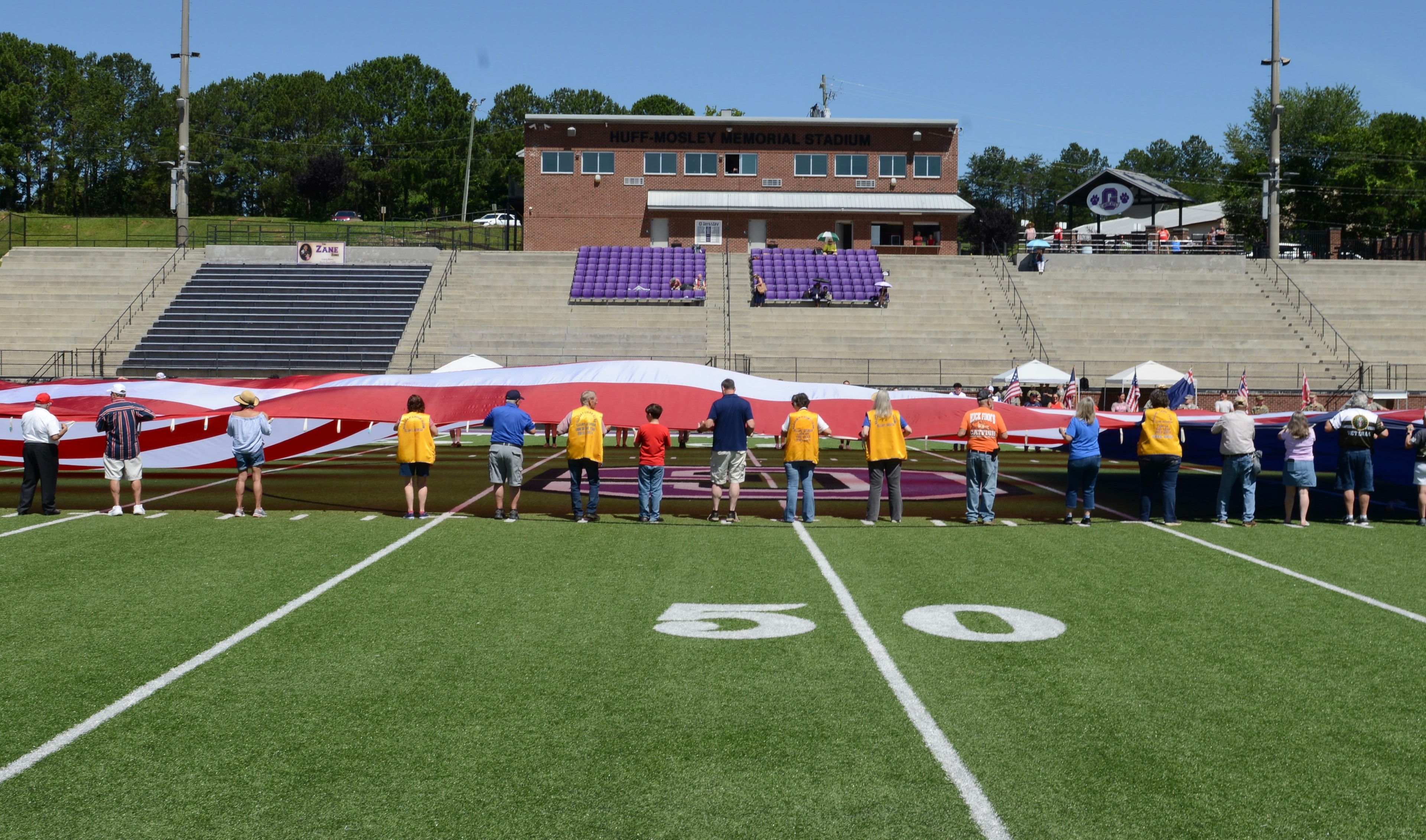 Lions Club members and volunteers holding the giant American flag at the 50-yard line at Pettit Field