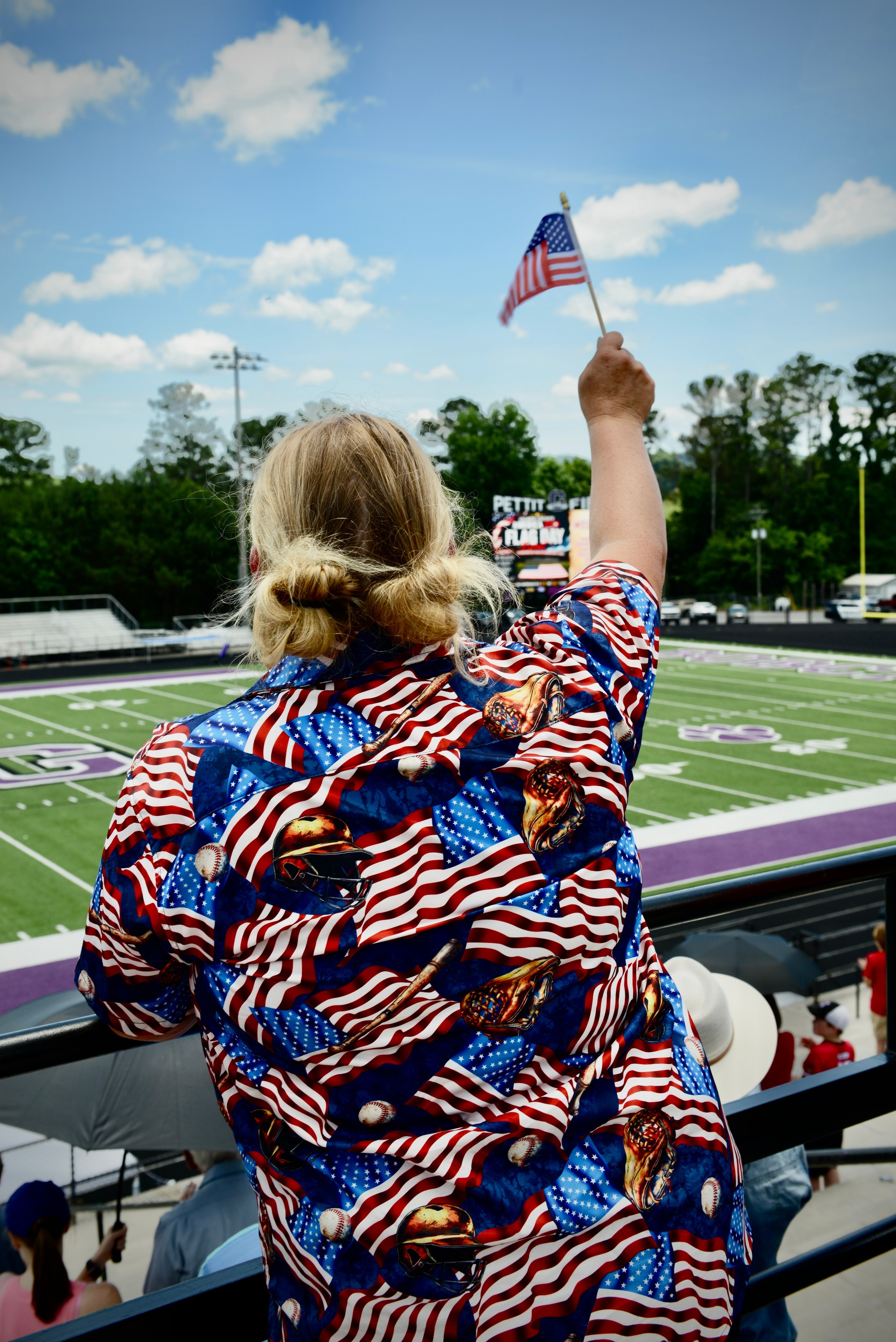 Community member waving a small American flag from the stands at the Flag Day event