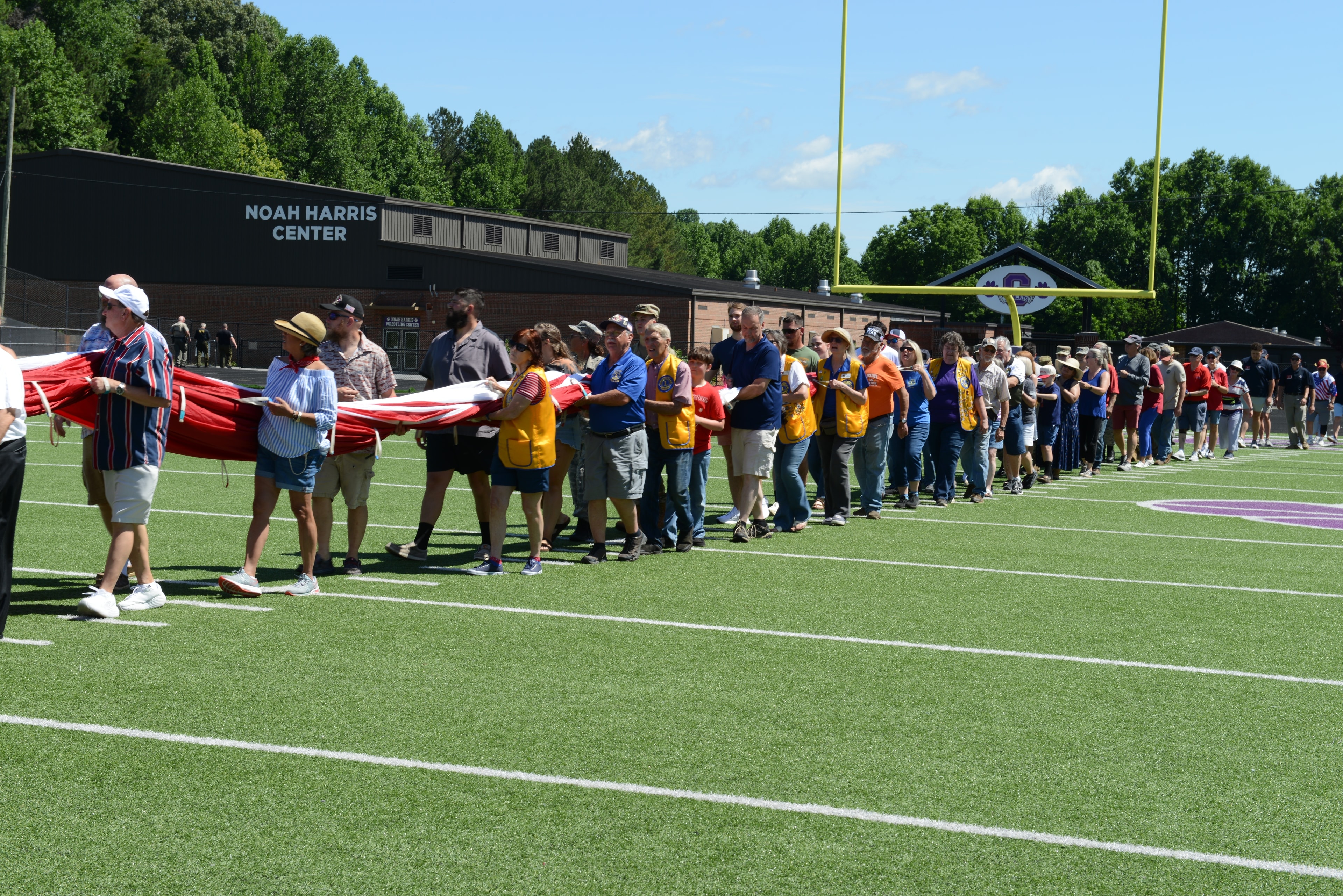Lions Club members and community volunteers carrying a giant American flag at Pettit Field