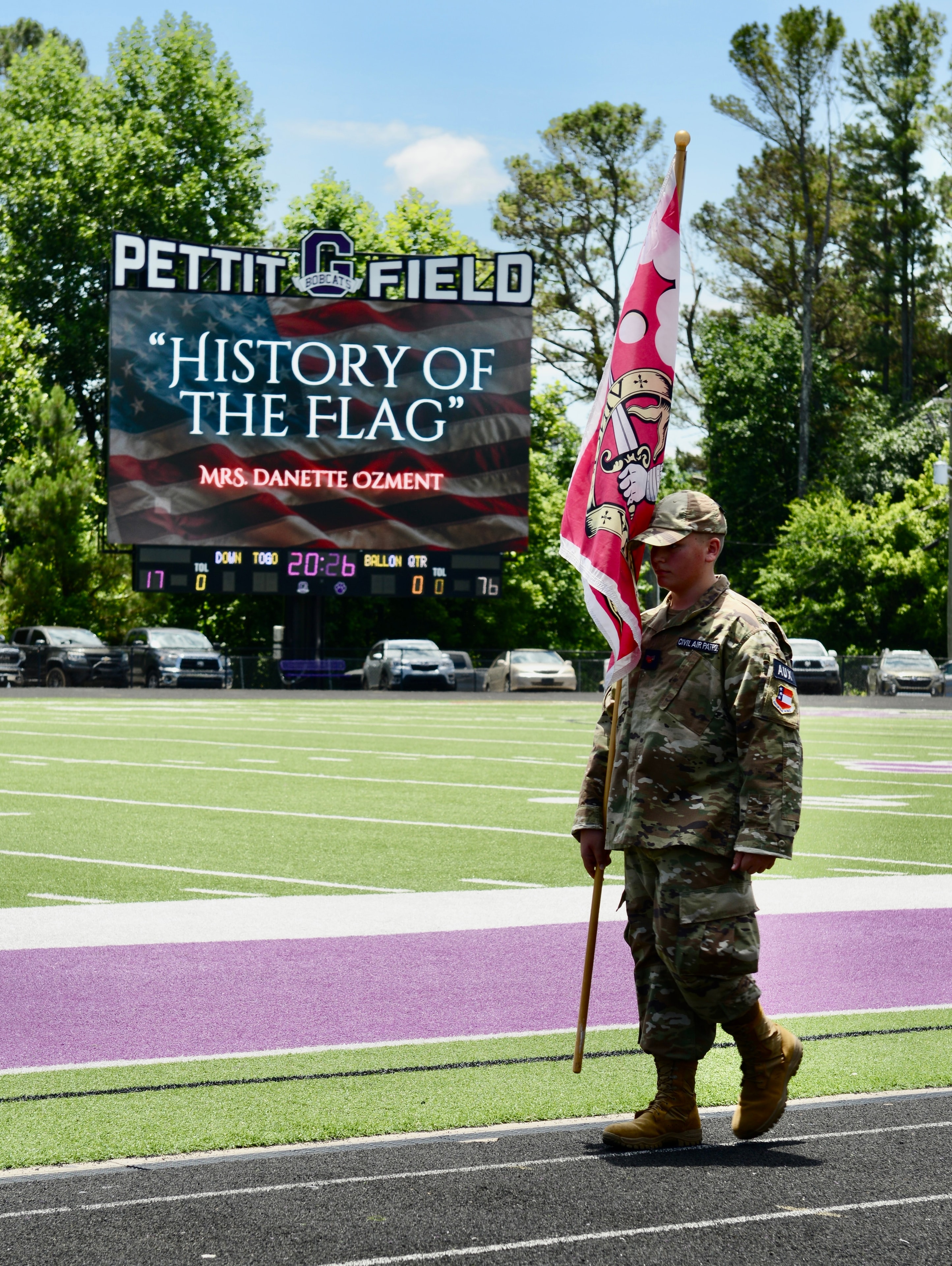 Military service member carrying flag at the Flag Day ceremony at Pettit Field