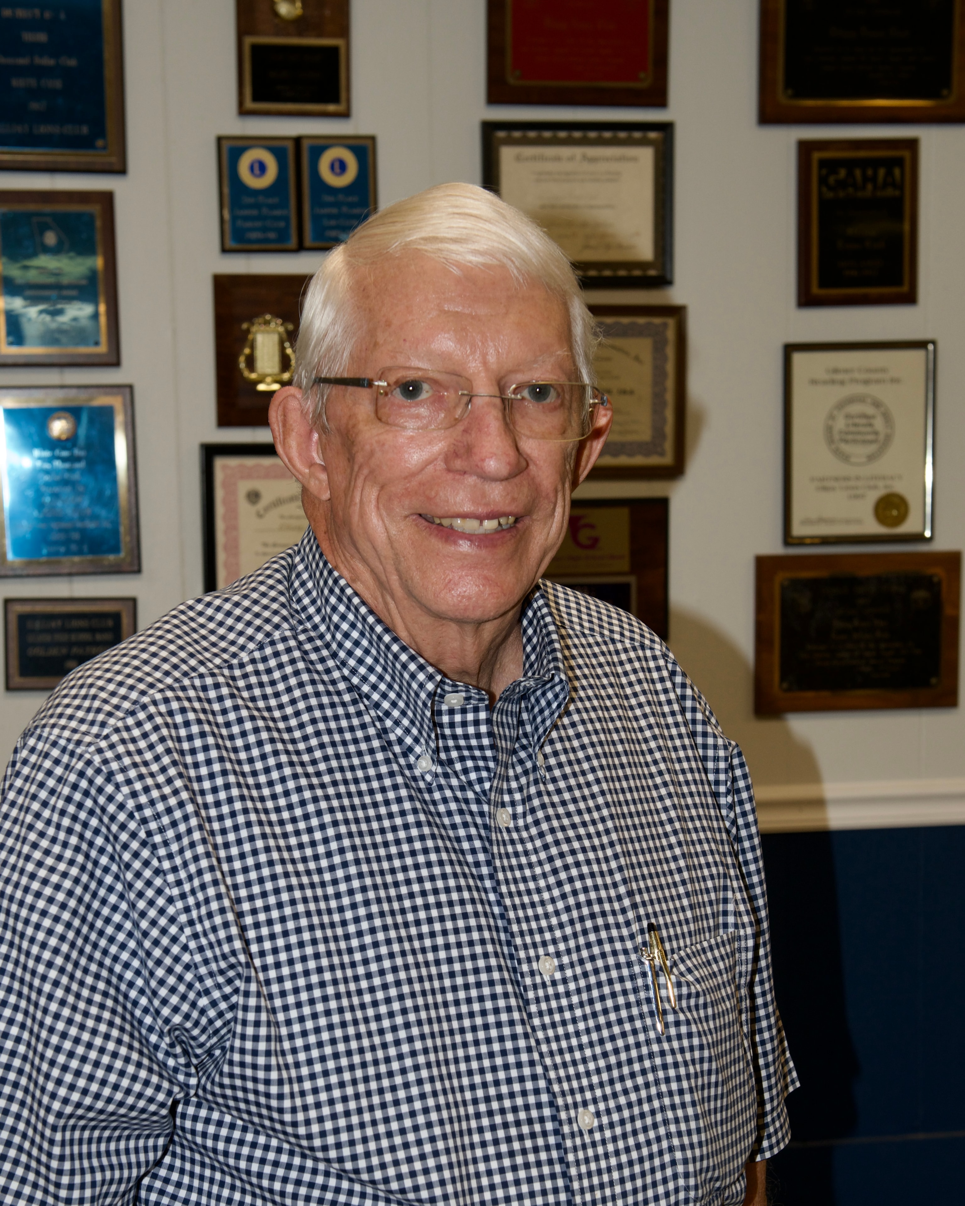 Portrait of guest speaker smiling in front of Lions Club award wall