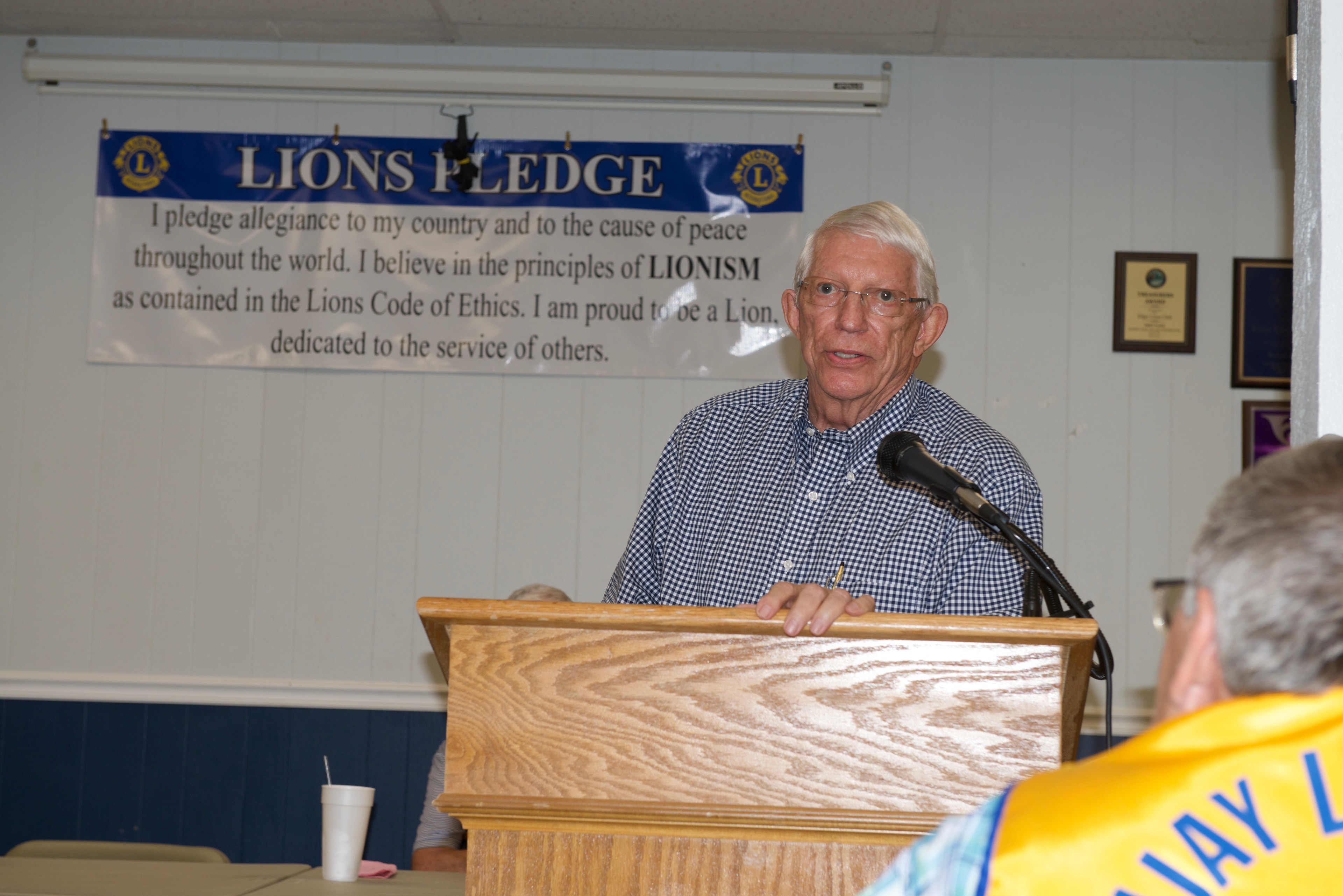 Guest speaker at the podium with the Lions Pledge banner behind him