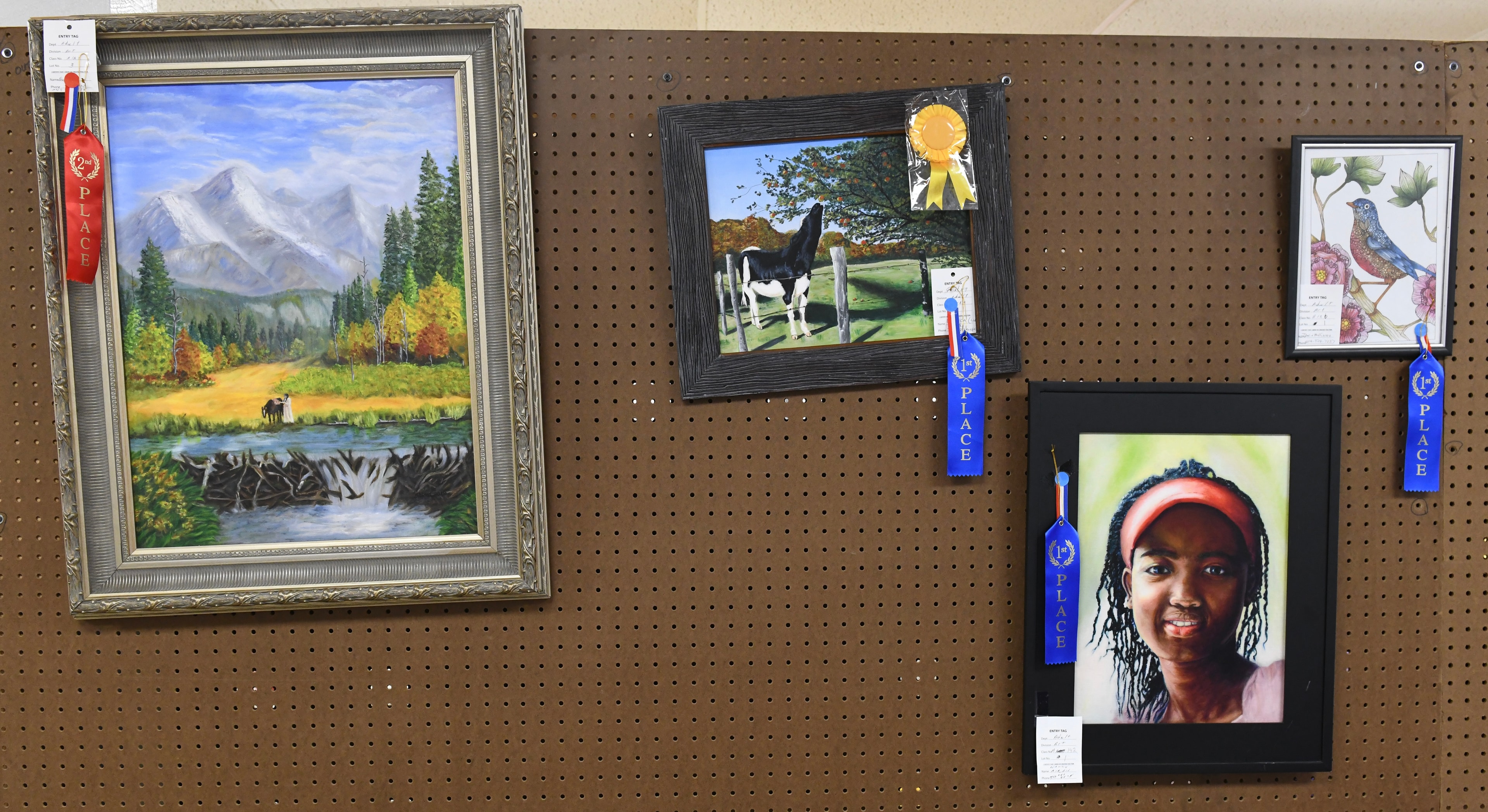 Award-winning artwork displayed on pegboard wall at the Gilmer County Fair