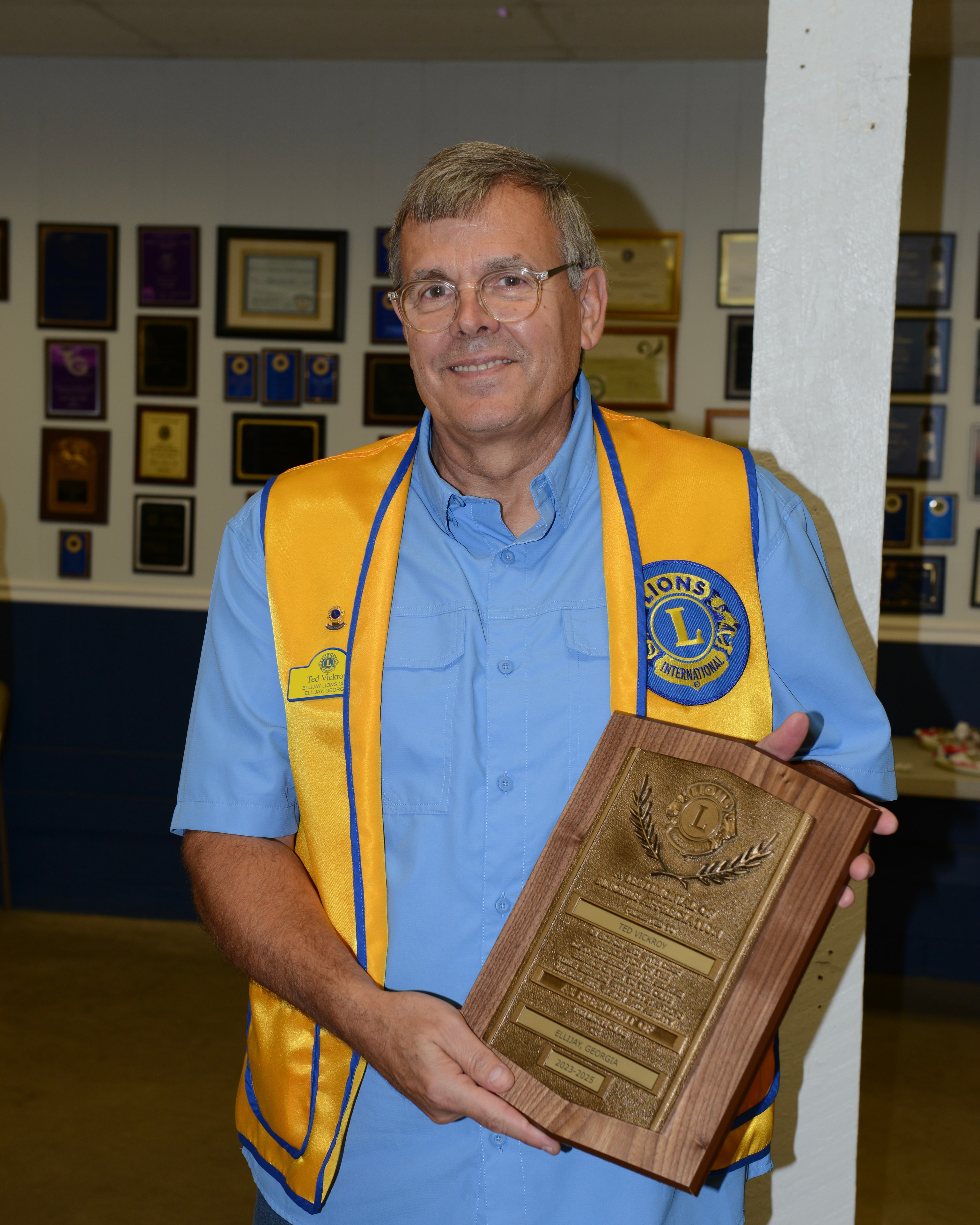 Lions Club member holding an award plaque at the ceremony