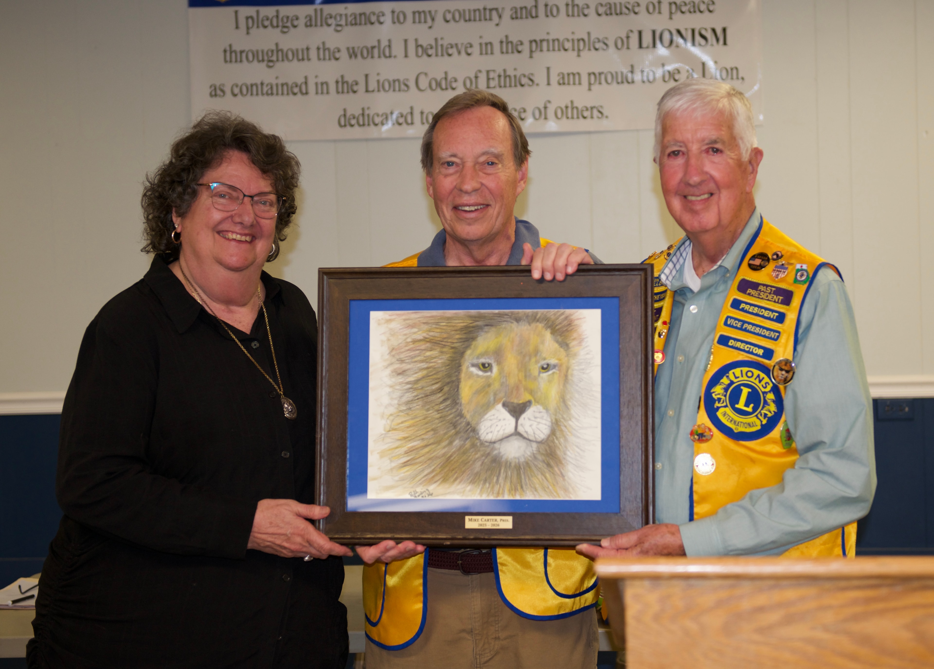 Lions Club members presenting a framed lion artwork at the ceremony